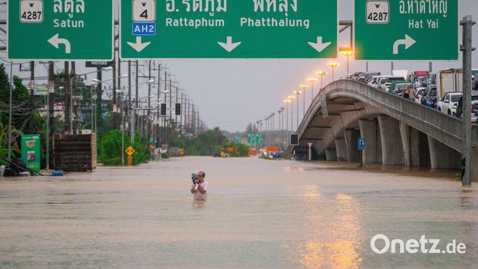 Ein Mann watet durch die Fluten in einem Vorort von Hat Yai in Thailand. Bild: -/XinHua/dpa