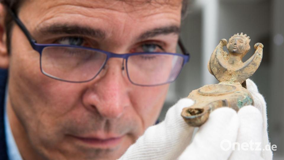 Augsburgs Stadtarchäologe Sebastian Gairhos betrachtet eine antike Öllampe, die vor wenigen Jahren in Bayerns ältestem Römerlager entdeckt wurde. (Archivbild) Bild: Stefan Puchner/dpa