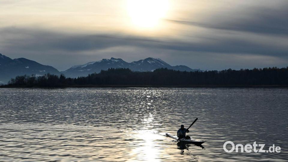 Ein Kajakfahrer fährt vor schneebedeckten Bergen über den Chiemsee. Bild: Katrin Requadt/dpa