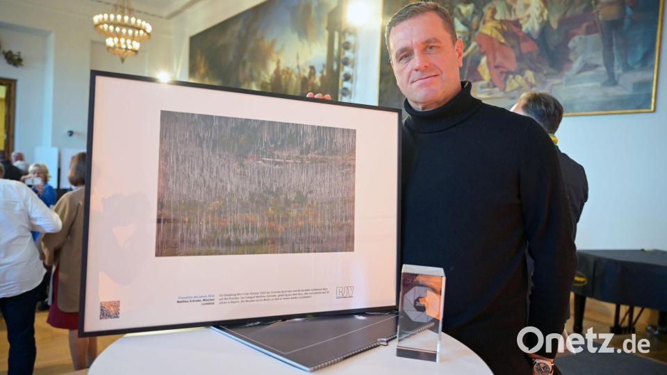 Der Münchner Fotograf Matthias Schrader steht mit seiner Auszeichnung für das Pressefoto des Jahres 2025 bei der Preisverleihung „Pressefoto Bayern 2025“ im Bayerischen Landtag. Schraders Bild zeigt eine Dampfeisenbahn in einem von Borkenkäfern befallenen Wald im Harz. Bild: Malin Wunderlich/dpa