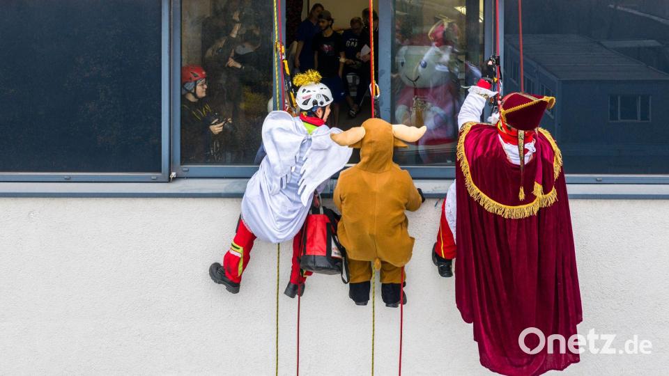 Verkleidete Höhenretter seilen sich von einem Gebäude des Herzzentrums Duisburg ab, um kleinen Patienten im Kinderherzzentrum Geschenke zu bringen. Bild: Christoph Reichwein/dpa