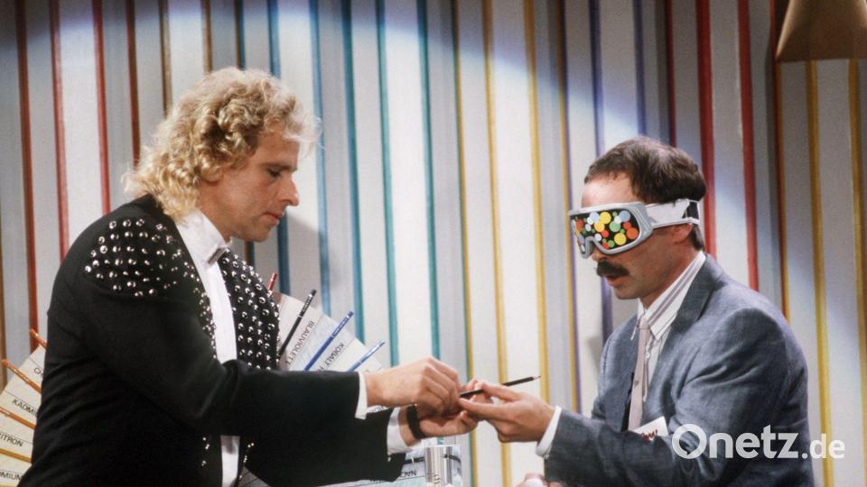 Gottschalk reicht seinem Wettkandidaten, dem damaligen Chefredakteur des Satiremagazins „Titanic“, Bernd Fritz, während der ZDF-Show „Wetten dass...?“ einen Buntstift. Bild: Bernd Weissbrod/dpa