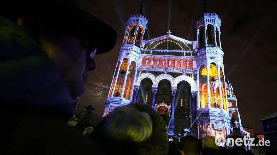 Menschen betrachten in Lyon die Basilika Notre-Dame de Fourviere. Bild: Laurent Cipriani/AP/dpa