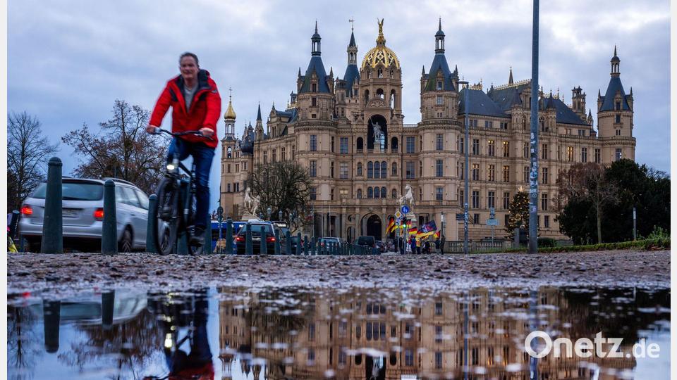 Fahrradfahrer vor dem Schweriner Schloss bei mildem, grauem Wetter in Norddeutschland. Bild: Jens Büttner/dpa