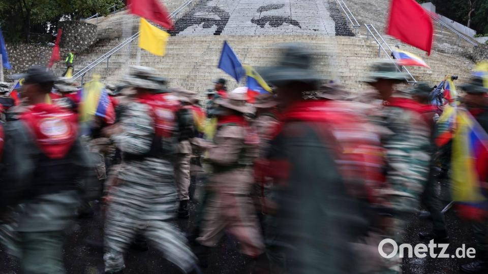 Mitglieder der Bolivarischen Miliz marschieren vor einer Treppe in Caracas, auf der die Augen des verstorbenen Präsidenten Hugo Chavez abgebildet sind, während einer Demonstration zum Gedenken an den Jahrestag der Schlacht von Santa Ines, die während des venezolanischen Bundeskriegs im 19. Jahrhundert stattfand. Bild: Jesus Vargas/dpa