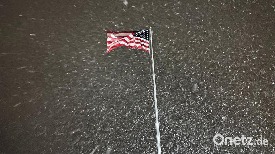 Eine Flagge weht im Wind, während in Lowville in den USA Schnee fällt. Bild: Cara Anna/AP/dpa