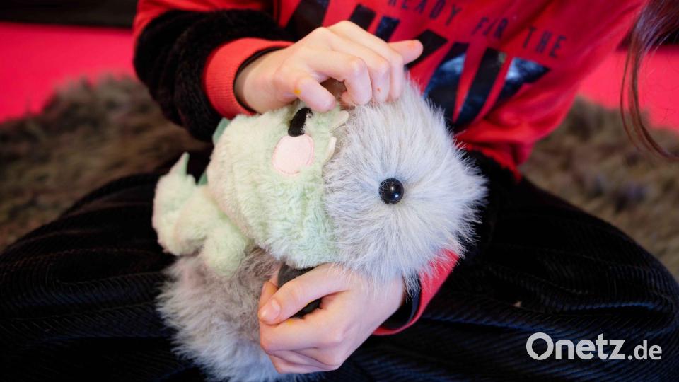 Mathilda beschäftigt sich im Zentrum für Kunst und Medien Karlsruhe im elektronischen Streichelzoo mit einem Roboter, der nicht nur aussieht wie ein  Meerschweinchen, sondern auch kuschelig ist, schnurren und auf Berührung reagieren kann. Bild: Uwe Anspach/dpa