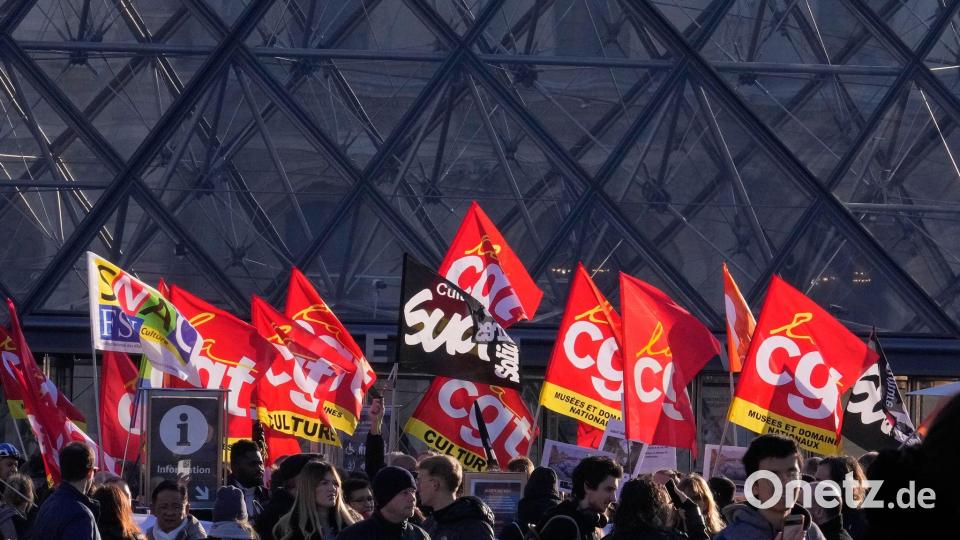 Angestellte zeigen Fahnen der Gewerkschaft CGT vor dem Louvre. Bild: Michel Euler/AP/dpa