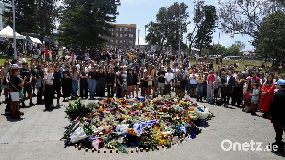 Menschen versammelt sich einen Tag nach einer Schießerei am Bondi Beach in Sydney um ein Blumendenkmal. Bild: Mark Baker/AP/dpa