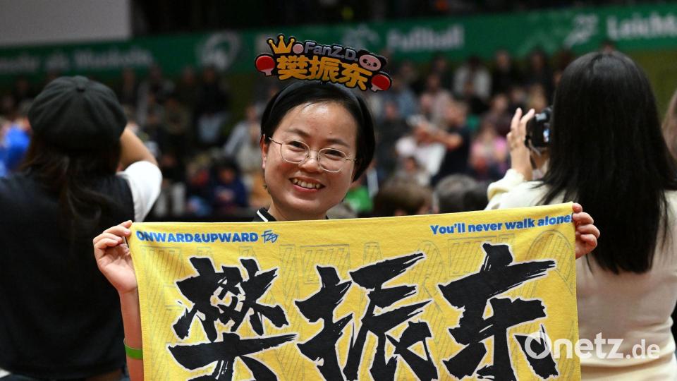 Eine chinesische Anhängerin hält beim Bundesliga-Spiel zwischen Werder Bremen und dem 1. FC Saarbrücken ein chinesisches Fanplakat hoch. Bild: Carmen Jaspersen/dpa