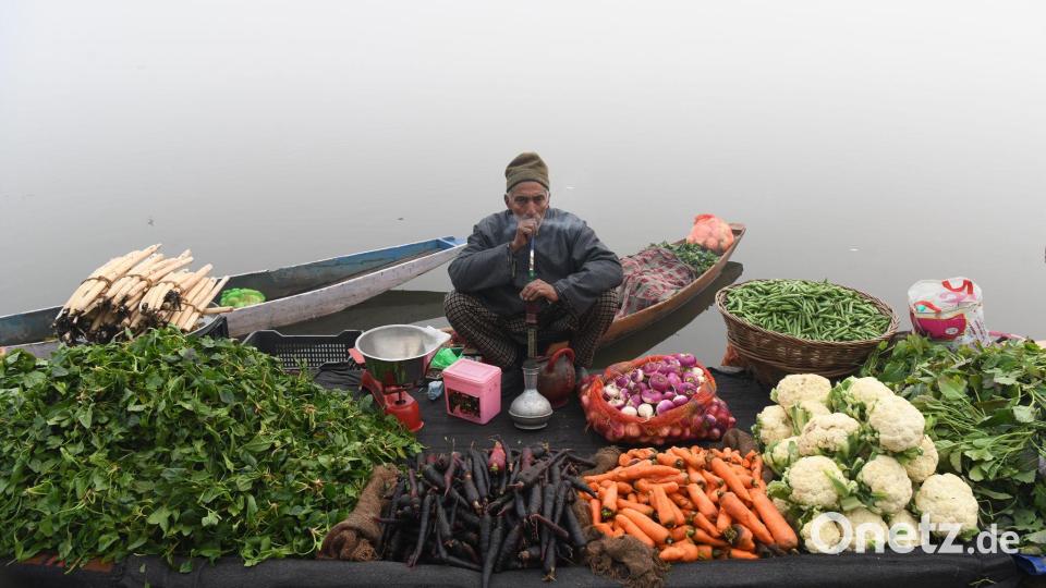 Ein Gemüsehändler raucht eine Wasserpfeife, während er an einem nebligen Tag am Ufer eines Sees im indischen Srinagar auf Kunden wartet. Bild: Basit Zargar/ZUMA Press Wire/dpa
