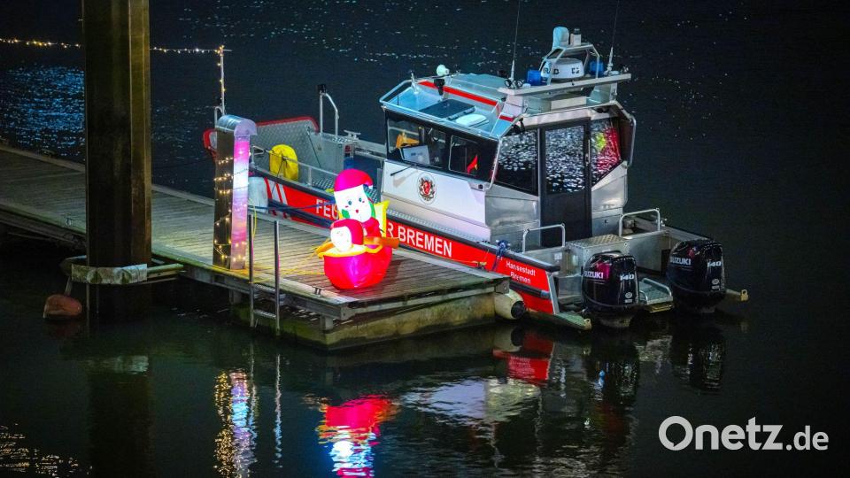 Ein leuchtender Weihnachtsmann steht neben einem Boot der Feuerwehr an der Weser in Bremen. Bild: Sina Schuldt/dpa