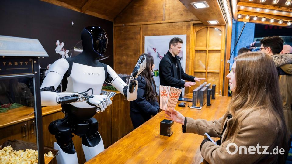 Der humanoide Roboter „Optimus“ von Tesla verteilt bei seiner Vorstellung in der Mall of Berlin Popcorn an eine Besucherin. Bild: Christoph Soeder/dpa