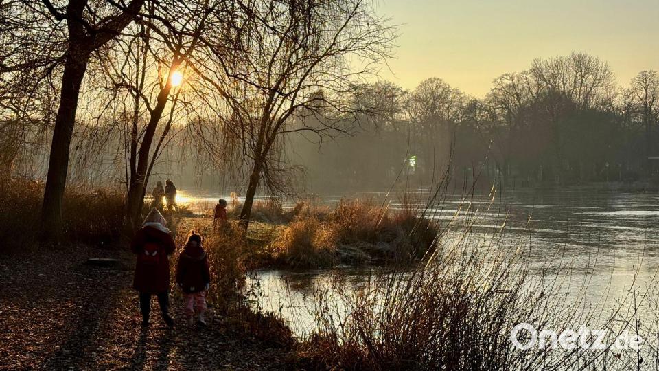 Spaziergänger sind am zugefrorenen Schloßteich in Chemnitz unterwegs. Bild: Hendrik Schmidt/dpa