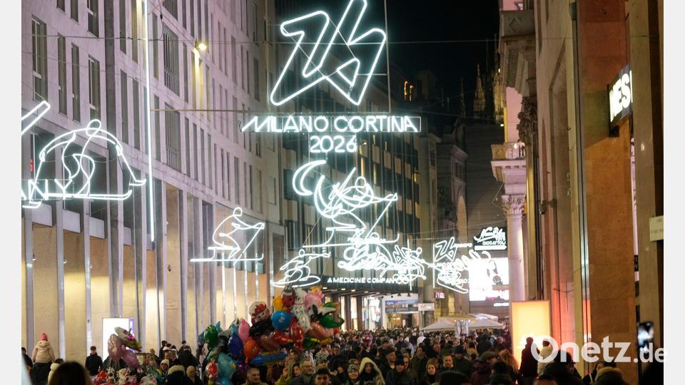 Menschen spazieren durch das Stadtzentrum Mailands, welches mit Beleuchtung für die bevorstehenden Olympischen Winterspiele in Italien 2026 geschmückt ist. Bild: Luca Bruno/AP/dpa