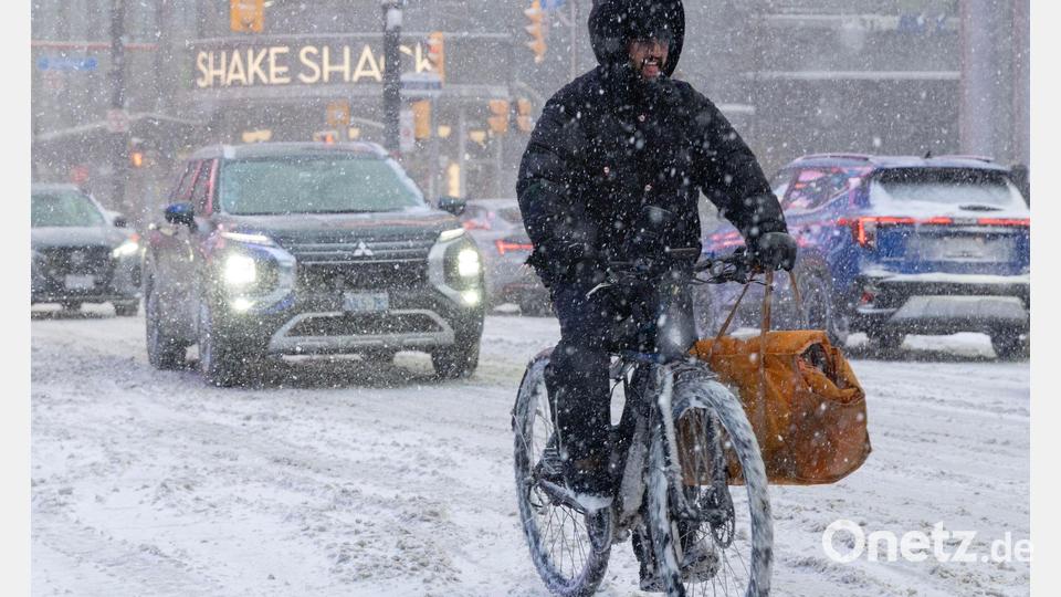 Ein Mann fährt an einem verschneiten Tag in Toronto auf einem E-Bike. Bild: Zou Zheng/XinHua/dpa