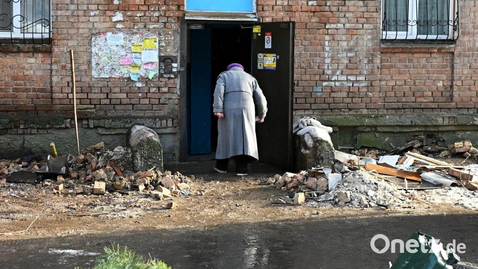 Eine Frau geht in ein beschädigtes Haus. Bild: Aleksandr Gusev/SOPA Images via ZUMA Press Wire/dpa
