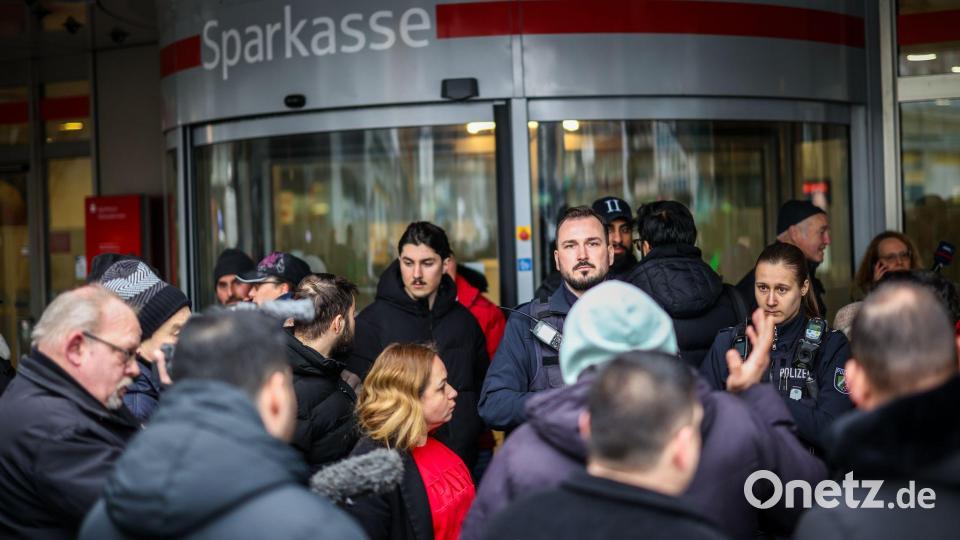 Polizeibeamte sprechen mit möglicherweise betroffenen Kunden der Sparkassenfiliale in Buer. Bild: Christoph Reichwein/dpa