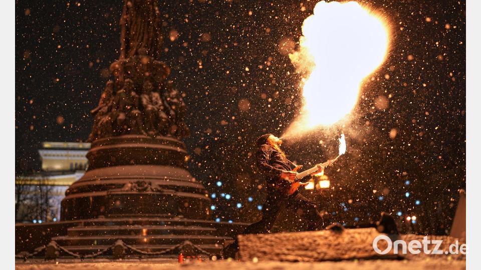 Heiß und kalt: Ein Straßenkünstler führt bei Schneefall eine Feuershow im russischen St. Petersburg auf. Bild: Dmitri Lovetsky/AP/dpa