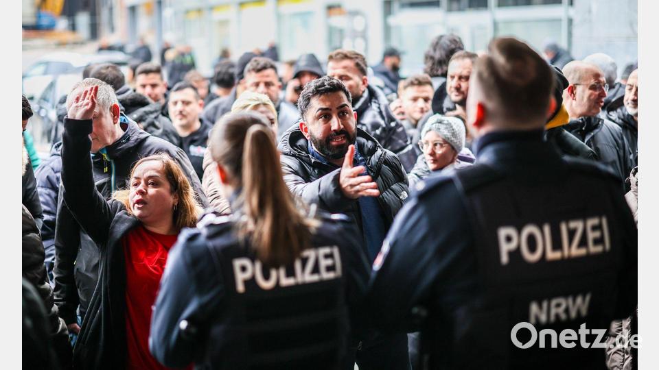 Aufgebrachte Kunden diskutieren vor der Sparkassenfiliale in Buer mit Polizeibeamten nach der Räumung des Vorraums der Filiale. Bild: Christoph Reichwein/dpa