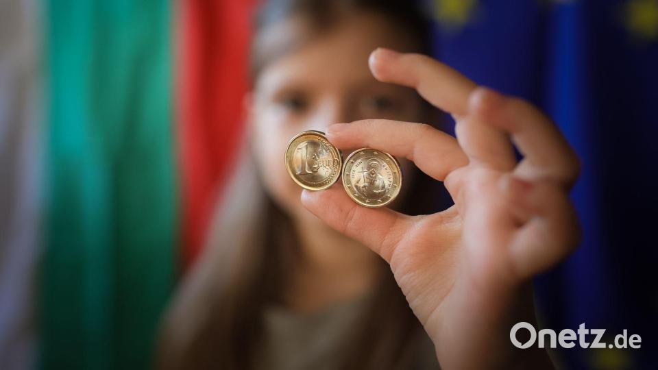 Ein Mädchen zeigt neue Euro-Münzen mit bulgarischen Symbolen. Bild: Valentina Petrova/AP/dpa