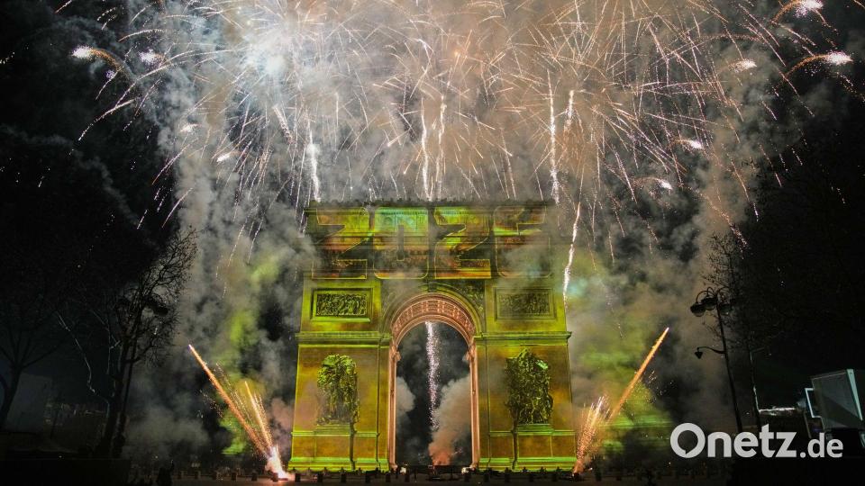 Eine Lichtshow wird auf den Arc de Triomphe projiziert, während ein Feuerwerk im Rahmen der Neujahrsfeierlichkeiten auf den Champs Elysees gezündet wird. Bild: Christophe Ena/AP/dpa