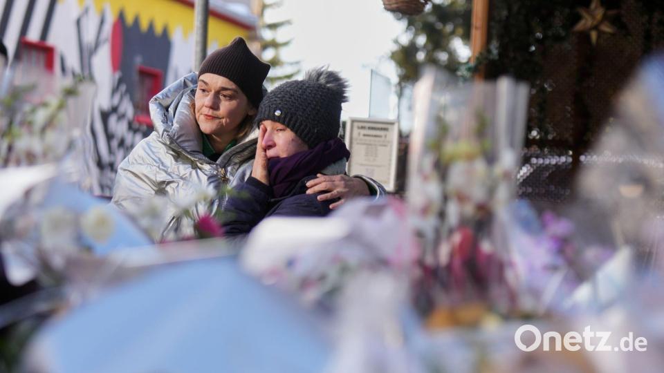 Menschen trauern hinter Blumen und Briefen in der Nähe der abgeriegelten Le Constellation Bar, wo ein verheerender Brand während der Neujahrsfeierlichkeiten Tote und Verletzte forderte. Bild: Antonio Calanni/AP/dpa