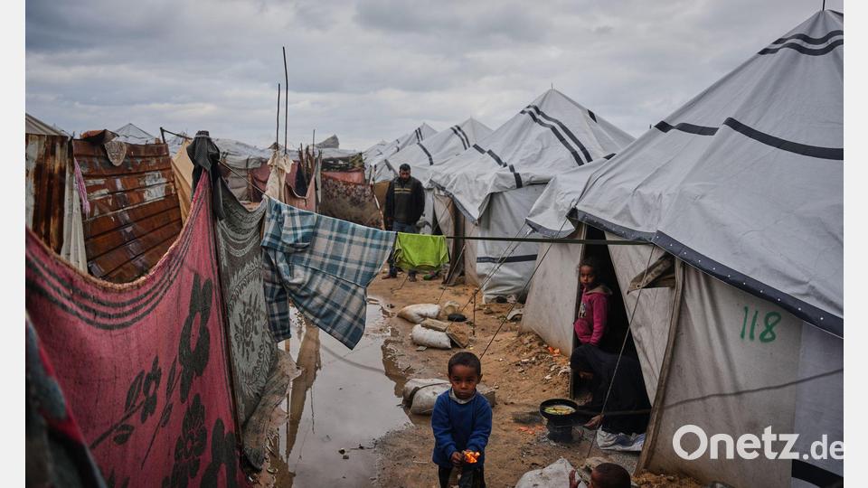 Nanaa Abu Jari kocht in Nuseirat im zentralen Gazastreifen vor ihrem Zelt, das von Regenwasser überflutet wurde.. Bild: Abdel Kareem Hana/AP/dpa