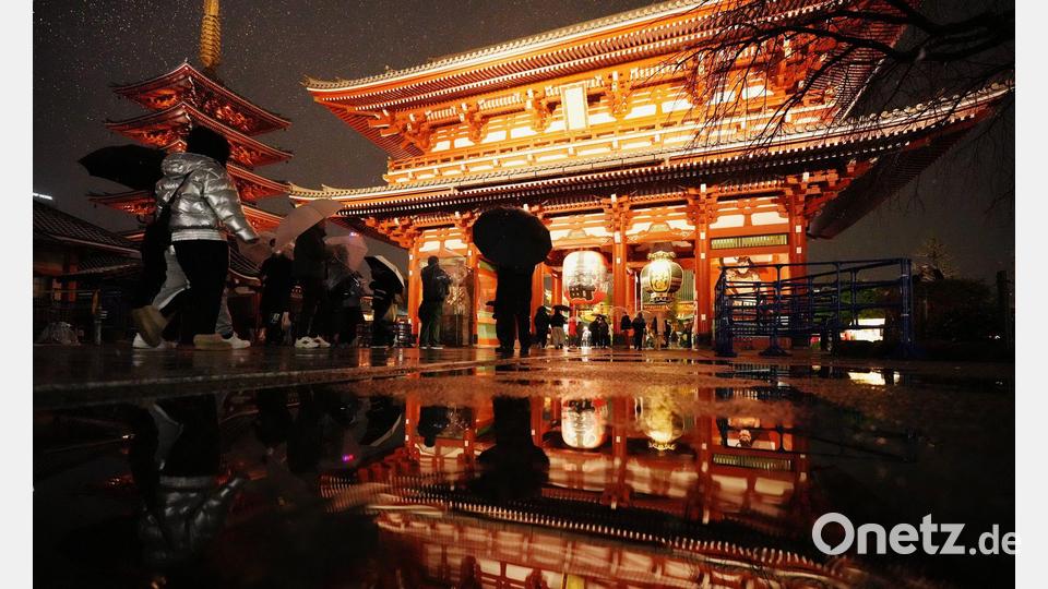 Der Sensoji-Tempel spiegelt sich in einer Pfütze, als Menschen zum Neujahrsgebet in Tokio ankommen. Bild: Hiro Komae/AP/dpa