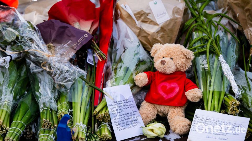 Menschen legen Blumen, Teddys und Botschaften am Brandort ab. Bild: Jean-Christophe Bott/KEYSTONE/dpa