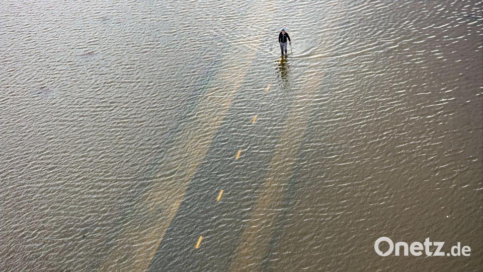 Ein Mensch geht auf einem überfluteten Weg während einer Springflut in Kalifornien. Bild: Ethan Swope/FR171736 AP/AP/dpa