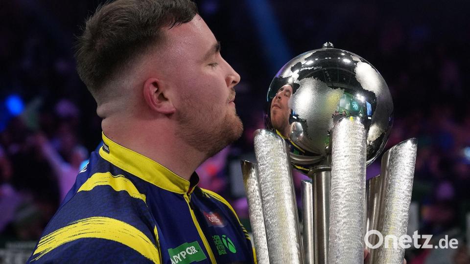 Luke Littler küsst die Trophäe nach seinem Sieg im Endspiel der Darts-WM. Bild: Dave Shopland/AP/dpa