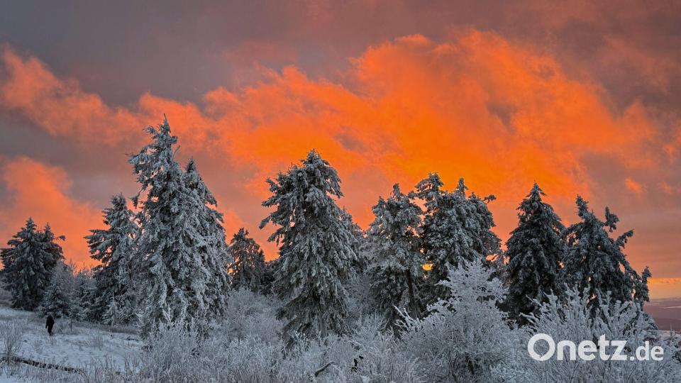 Das Licht der untergehenden Sonne beleuchtet die Wolken, die hinter den schneebedeckten Bäumen auf dem Feldbergplateau untergeht. Bild: Boris Roessler/dpa