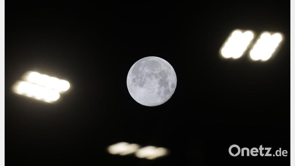 Blick auf den Mond zwischen Straßenlaternen in Riedlingen. Bild: Thomas Warnack/dpa