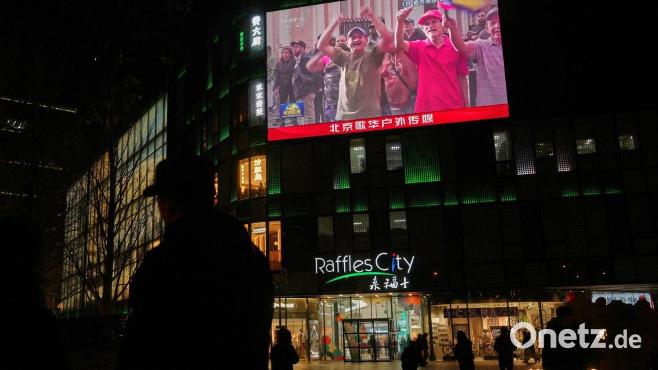 Menschen beobachten in China eine Übertragung einer Kundgebung aus Caracas. Bild: Andy Wong/AP/dpa