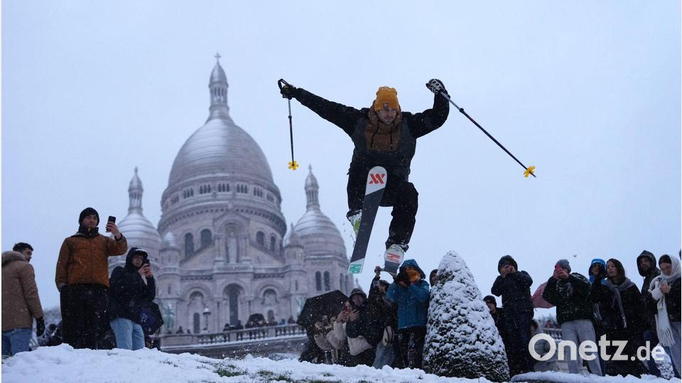Ein Mann springt mit seinen Skiern den Hügel bei der Basilika Sacre-Coeur hinunter, während es im Viertel Montmartre schneit. Bild: Aurelien Morissard/AP/dpa
