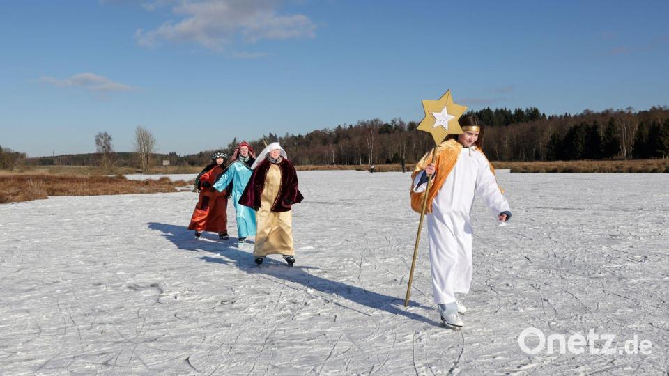 Sternsinger sind im Sonnenschein bei Betzenweiler in Tiefenbach mit Schlittschuhen auf einem zugefrorenen See unterwegs. Bild: Thomas Warnack/dpa