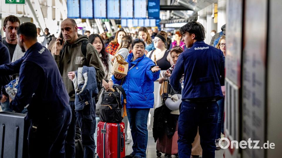 Reisende stehen Schlange am Serviceschalter der Fluggesellschaft KLM am Flughafen Schiphol. Bild: Robin Utrecht/ANP/dpa