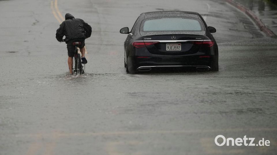 Ein Radfahrer fährt durch eine überflutete Straße. Bild: Jeff Chiu/AP/dpa