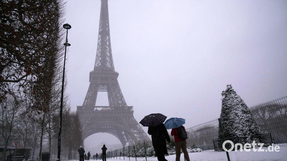 Es schneit unter dem Eiffelturm. Bild: Christophe Ena/AP/dpa