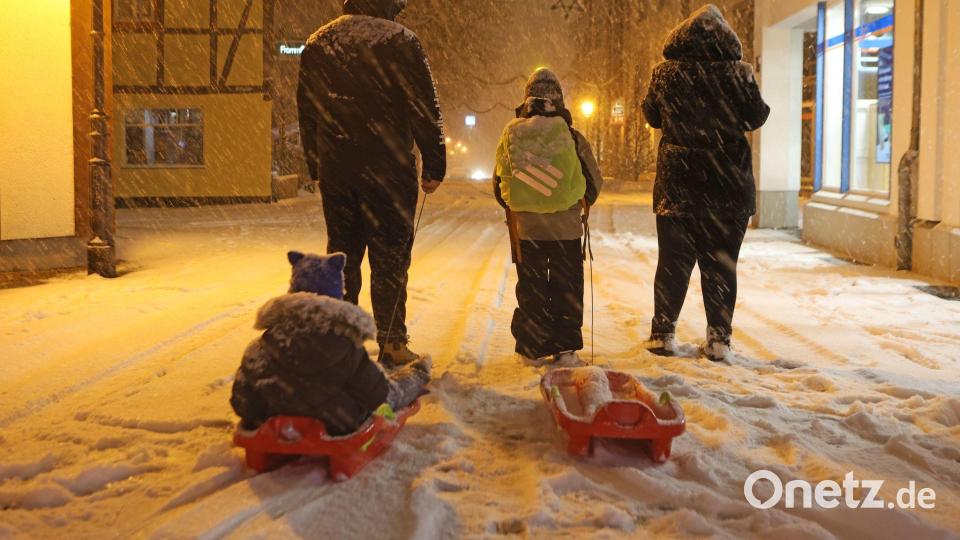 Eltern bringen am frühen Morgen in Wernigerode ihre Kinder mit Schlitten in die Schule. Wintersturm „Elli“ bringt Eiseskälte, Glätte und viel Schnee, so dass Busse und Bahnen teils nur eingeschränkt unterwegs sind. Bild: Matthias Bein/dpa