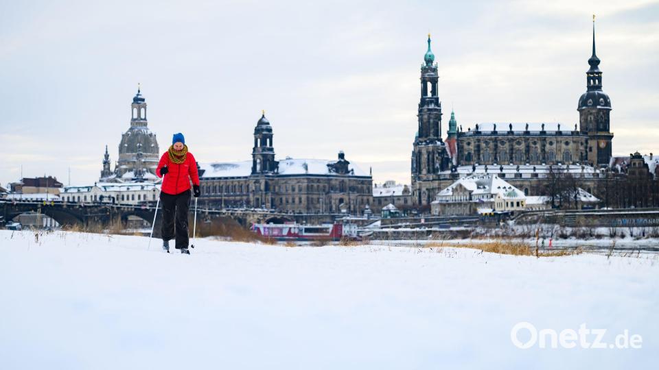 Eine Frau läuft am verschneiten Elbufer vor der historischen Altstadtkulisse in Dresden Ski Bild: Robert Michael/dpa