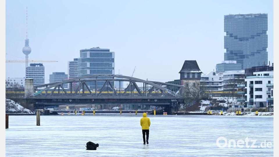 Ein Mann steht am Treptower Park in Berlin auf der zugefrorenen Spree. Bild: Elisa Schu/dpa