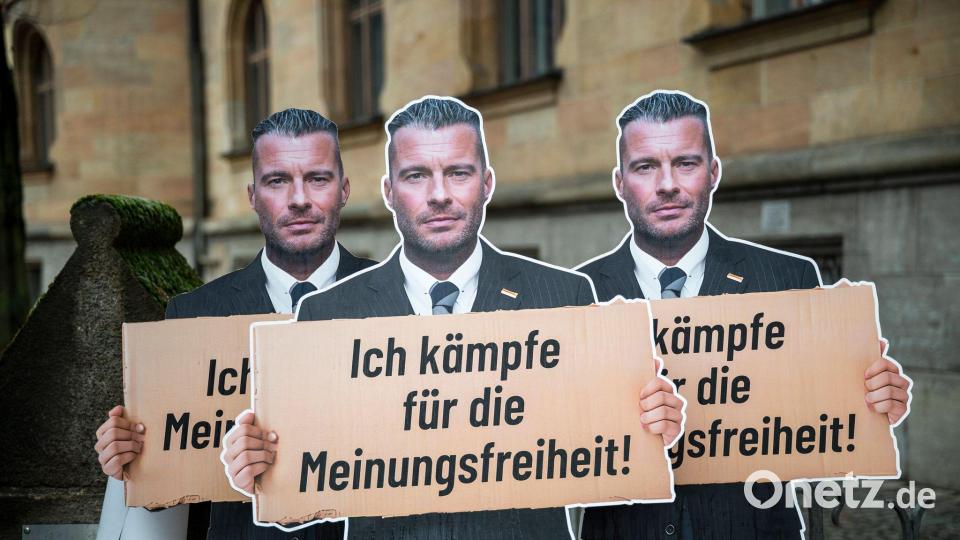 Vor dem Landgericht Bamberg stehen Pappaufsteller, die den Journalisten David Bendels mit einem Schild in der Hand zeigen - er selbst bezeichnete seinen Post als Satire. Bild: Daniel Vogl/dpa