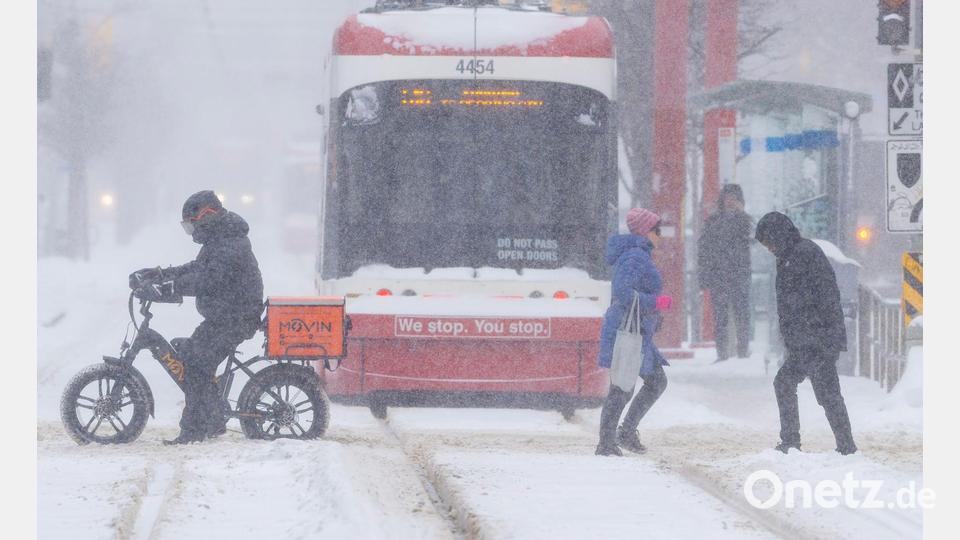 Menschen überqueren eine Straße an einem verschneiten Tag in Toronto, Kanada. Bild: Zou Zheng/XinHua/dpa