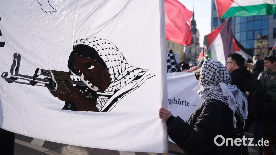 Teilnehmer einer propalästinensischen Demonstration stehen an einer Kreuzung im Stadtteil Connewitz in Leipzig und halten Fahnen und Transparente. Bild: Sebastian Willnow/dpa
