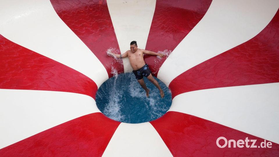 Ein Mann stürzt eine Wasserrutsche in einem öffentlichen Schwimmbad im Stadtteil Puente Piedra außerhalb von Lima hinunter. Bild: Martin Mejia/AP/dpa