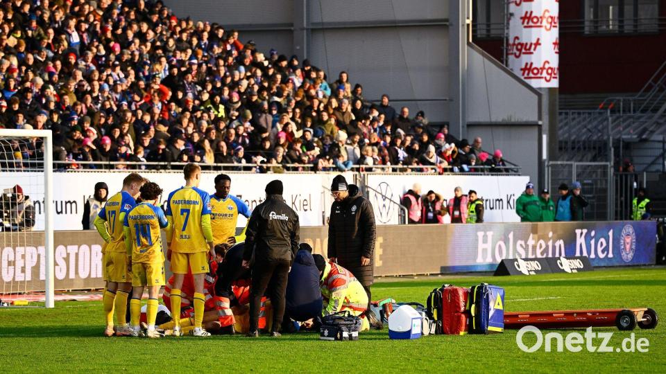 Paderborns Spieler Calvin Brackelmann wird auf dem Rasen von Sanitätern behandelt. Bild: Gregor Fischer/dpa