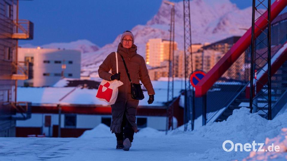 Eine Frau geht bei Sonnenuntergang auf einer Straße in Nuuk. Bild: Evgeniy Maloletka/AP/dpa