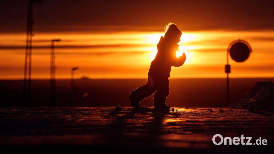Ein Junge läuft bei Sonnenuntergang über eine Straße in Nuuk in Grönland. Bild: Evgeniy Maloletka/AP/dpa